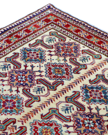 Tappeto Shirvan 165x122 cm con motivi geometrici e floreali in rosso, blu, verde e crema su fondo beige.