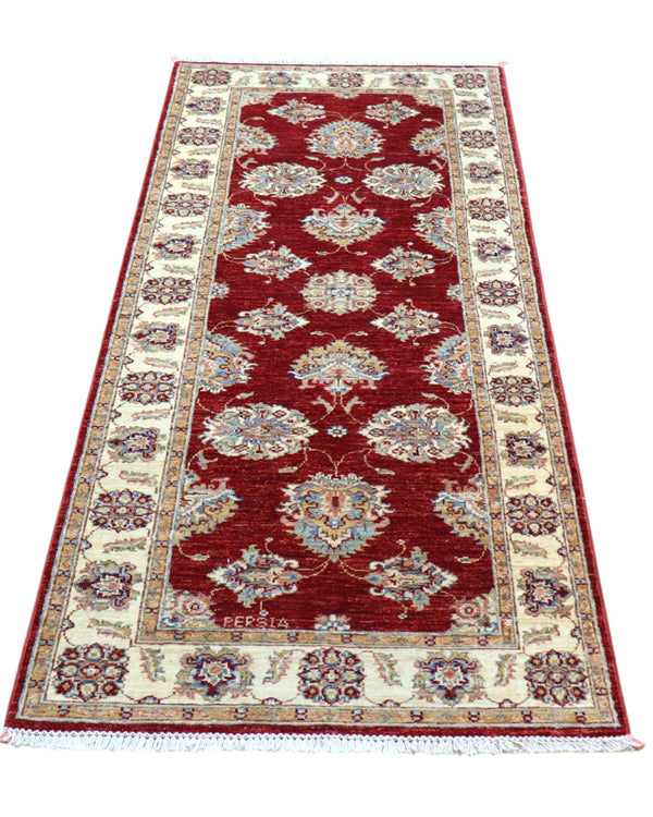 Tappeto Ziegler Afghan 199x83 cm annodato a mano, fondo rosso intenso con decorazioni floreali avorio e cornice chiara.