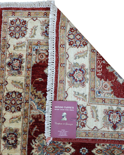 Tappeto Ziegler Afghan 199x83 cm annodato a mano, fondo rosso intenso con decorazioni floreali avorio e cornice chiara.
