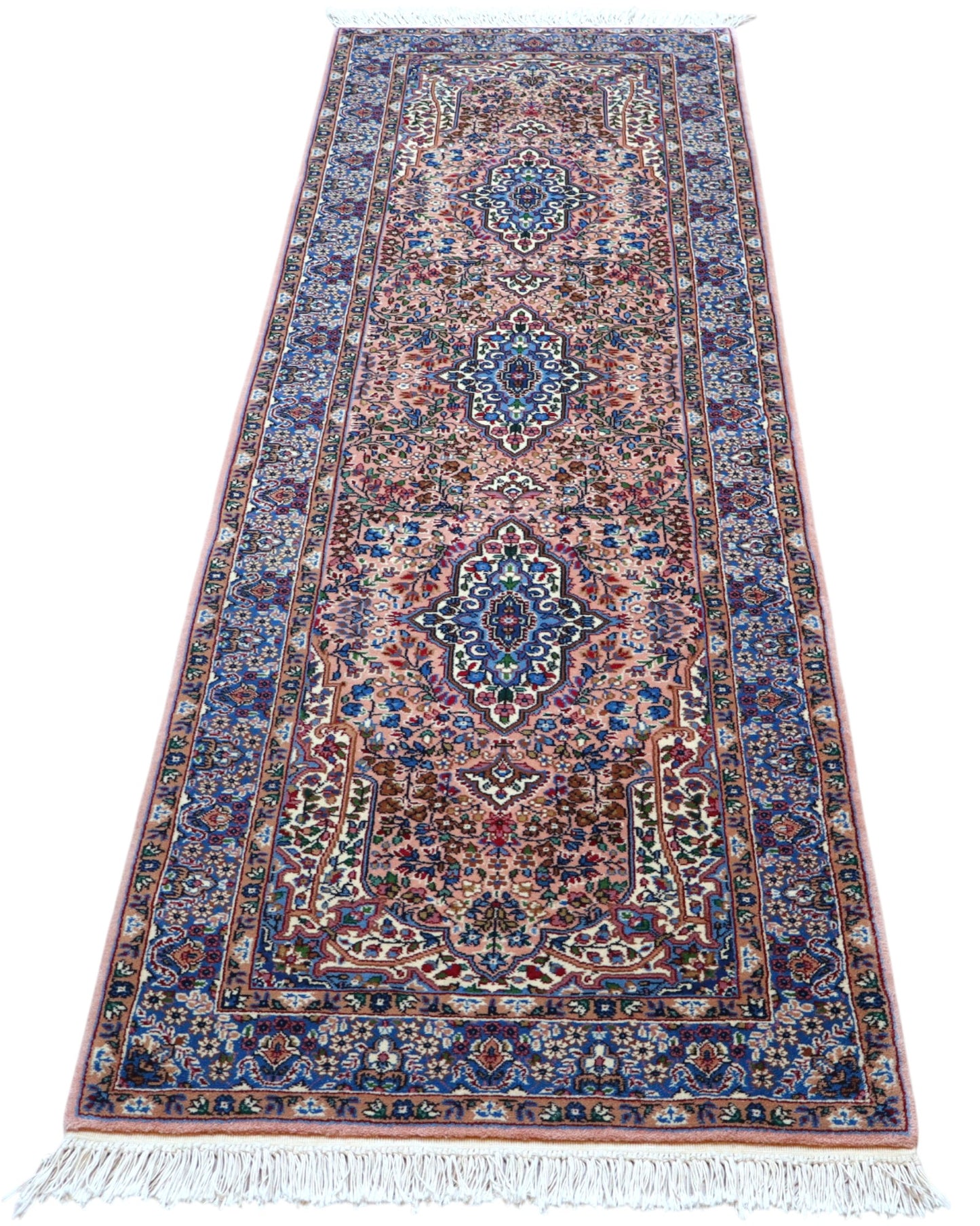 Tappeto persiano Kerman 247x77 cm, corridore con fondo rosa antico e motivi floreali blu e avorio, annodato a mano in lana vegetale.