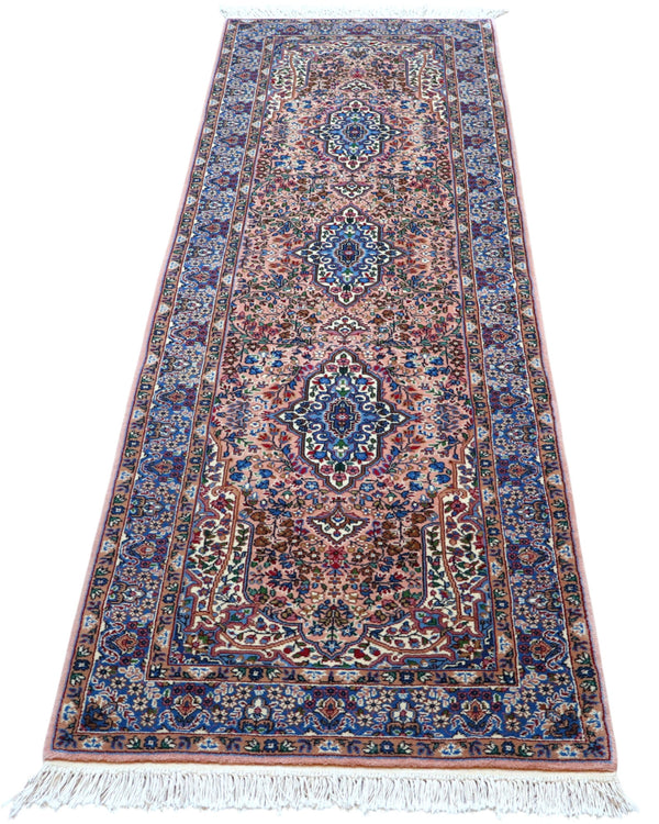 Tappeto persiano Kerman 247x77 cm, corridore con fondo rosa antico e motivi floreali blu e avorio, annodato a mano in lana vegetale.
