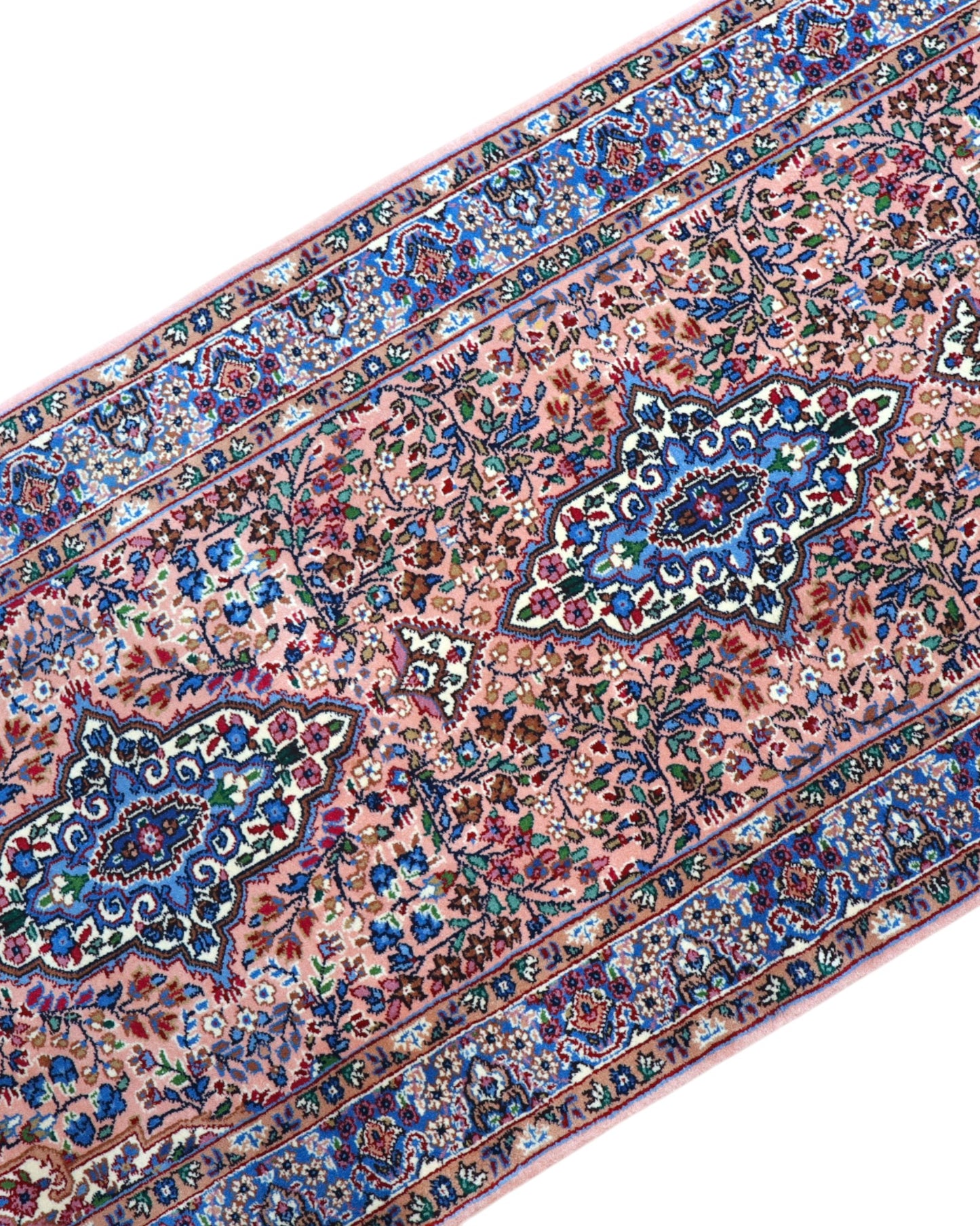 Tappeto persiano Kerman 247x77 cm, corridore con fondo rosa antico e motivi floreali blu e avorio, annodato a mano in lana vegetale.