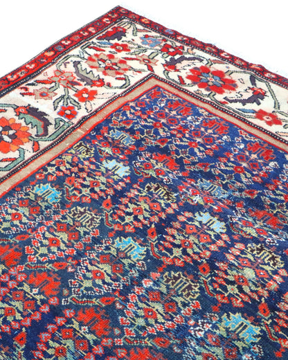 Tappeto Malayer antico 350x176 cm con fondo blu scuro, motivi geometrici rossi e avorio e bordura floreale vivace, tramato ed annodato a mano, provenienza Persia.