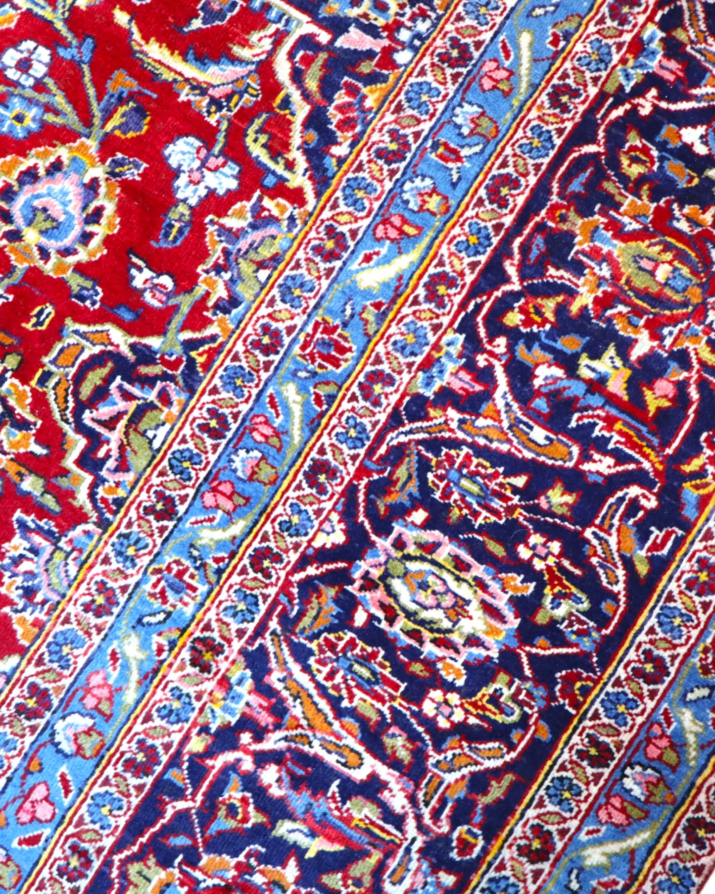 Tappeto persiano Kashan 402x297 cm, fondo rosso con medaglione centrale blu e avorio, annodato a mano in lana vegetale.