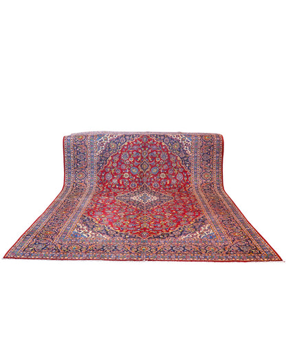Tappeto persiano Kashan 400x290 cm, fondo rosso con medaglione centrale blu e avorio, cornice scura floreale, annodato a mano in lana vegetale.