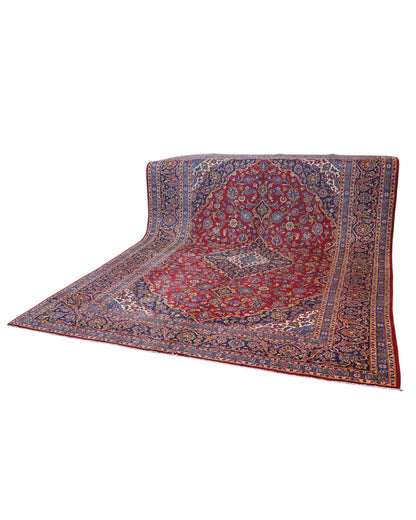 Tappeto persiano Kashan 400x290 cm, fondo rosso con medaglione centrale blu e avorio, cornice scura floreale, annodato a mano in lana vegetale.