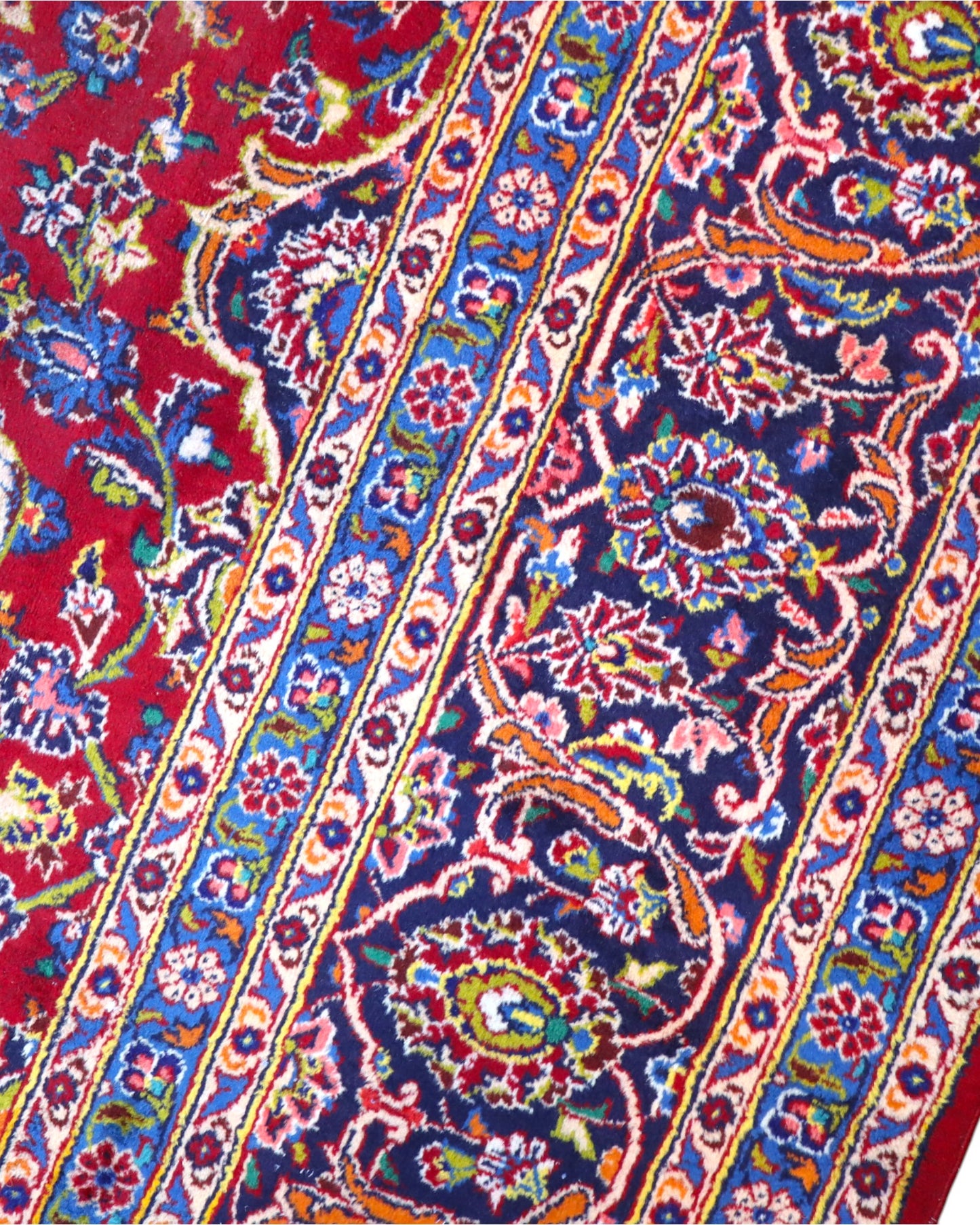 Tappeto persiano Kashan 400x290 cm, fondo rosso con medaglione centrale blu e avorio, cornice scura floreale, annodato a mano in lana vegetale.