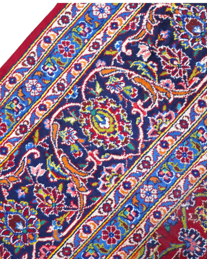 Tappeto persiano Kashan 400x290 cm, fondo rosso con medaglione centrale blu e avorio, cornice scura floreale, annodato a mano in lana vegetale.