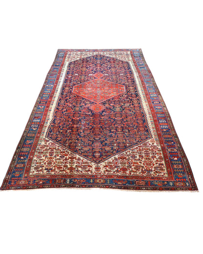 Tappeto persiano Malayer 390x297 cm, fondo blu con medaglione geometrico rosso, estremità avorio e cornice floreale, annodato a mano in lana vegetale.