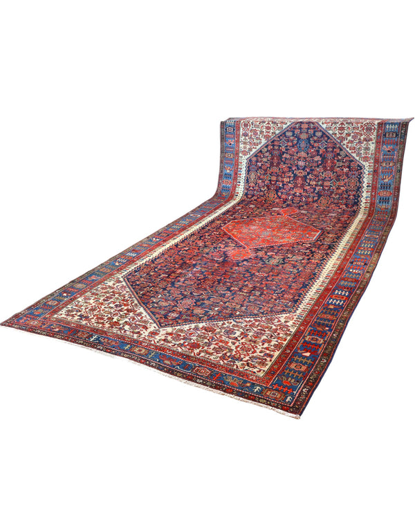 Tappeto persiano Malayer 390x297 cm, fondo blu con medaglione geometrico rosso, estremità avorio e cornice floreale, annodato a mano in lana vegetale.