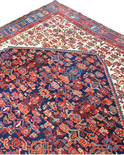 Tappeto persiano Malayer 390x297 cm, fondo blu con medaglione geometrico rosso, estremità avorio e cornice floreale, annodato a mano in lana vegetale.