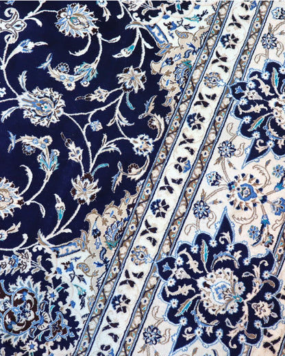Tappeto persiano Nain 390x297 cm, fondo blu notte con medaglione centrale e motivi floreali avorio e azzurro, annodato a mano in lana vegetale.
