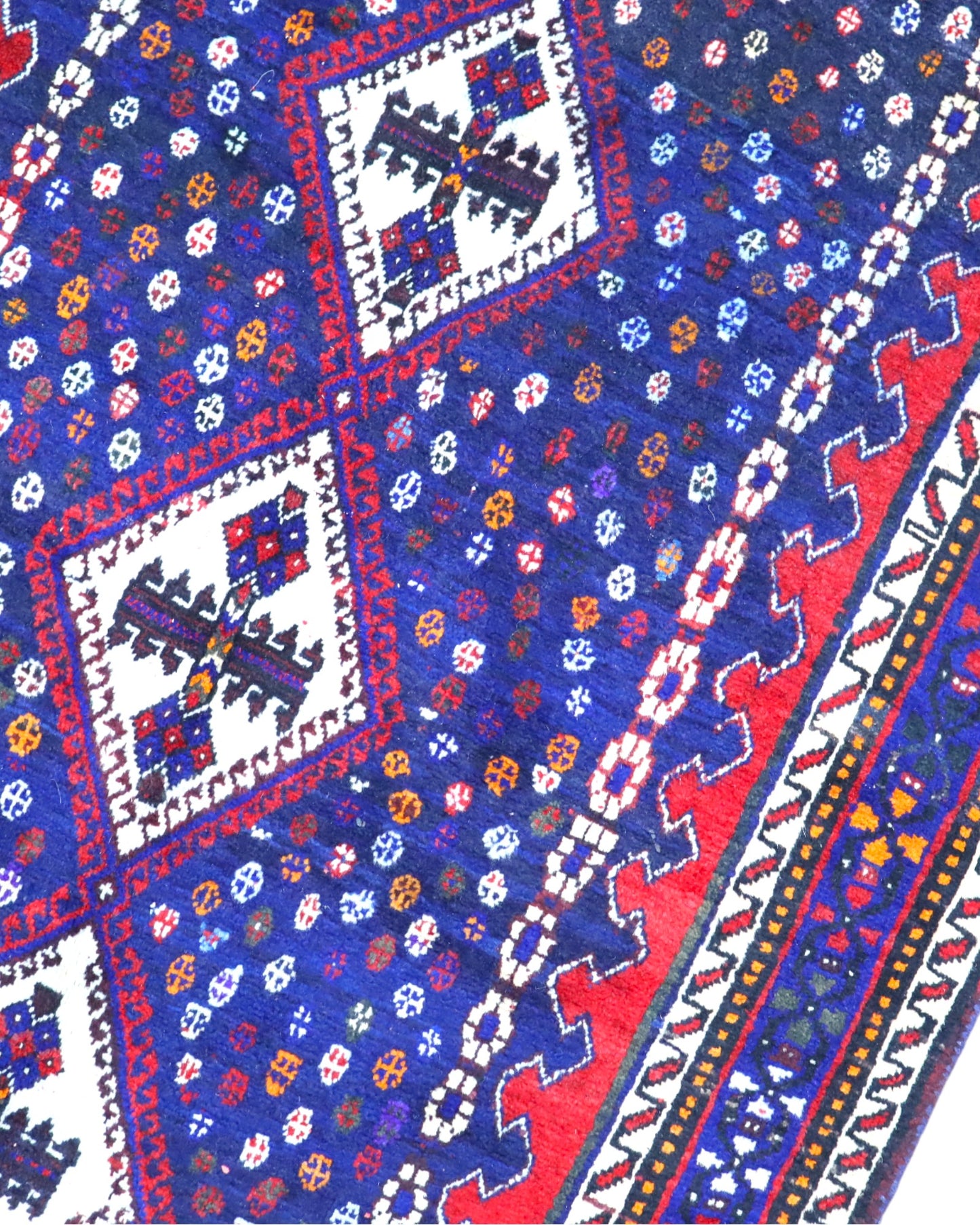 Tappeto Balucestan 215x100 cm annodato a mano, con sequenza di rombi centrali su fondo blu notte e bordi rosso granata.