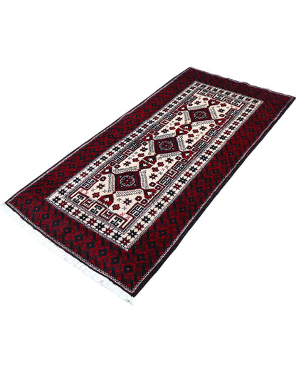 "Tappeto Balochistan 187x95 cm annodato a mano, fondo avorio con motivi geometrici rossi, neri e verdi."
