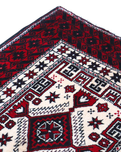 "Tappeto Balochistan 187x95 cm annodato a mano, fondo avorio con motivi geometrici rossi, neri e verdi."
