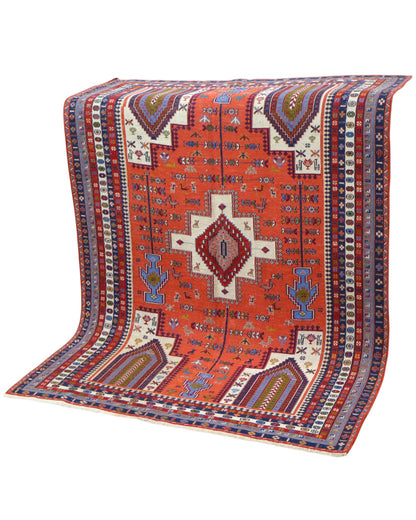 Tappeto Kilim 180x125 cm persiano tessuto a mano, con motivi geometrici tribali e medaglione centrale su fondo rosso mattone.