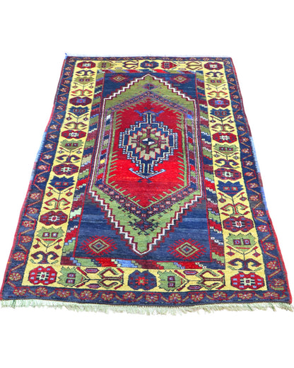 Tappeto Turco 179x103 cm, annodato a mano, con medaglione centrale geometrico rosso, motivi tribali e bordura gialla decorata.