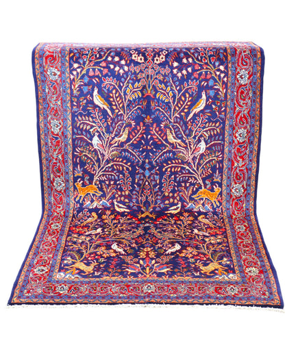 Tappeto Arak 210x126 cm persiano annodato a mano, con motivi floreali e animali su fondo blu intenso e cornice rossa decorata.