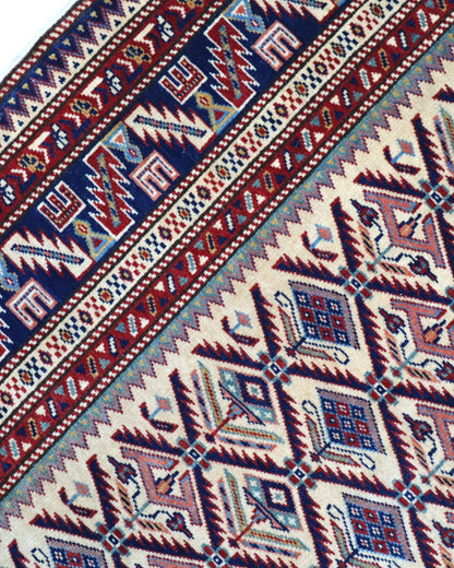 Tappeto Shirvan 167x122 cm in lana annodata a mano, fondo chiaro con rombi geometrici e cornice caucasica.