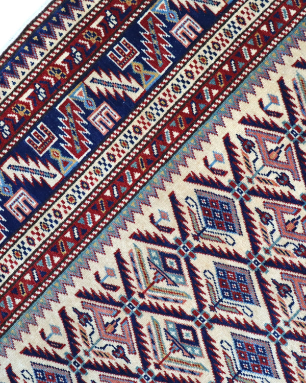 Tappeto Shirvan 167x122 cm in lana annodata a mano, fondo chiaro con rombi geometrici e cornice caucasica.