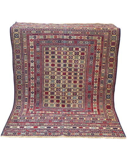 Tappeto Sumakh 180x130 cm con motivi geometrici e floreali in rosso, blu e crema su fondo beige.