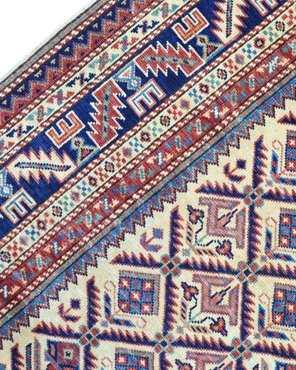 Tappeto Shirvan 166x120 cm in lana annodata a mano, fondo chiaro con rombi geometrici e cornici caucasiche.