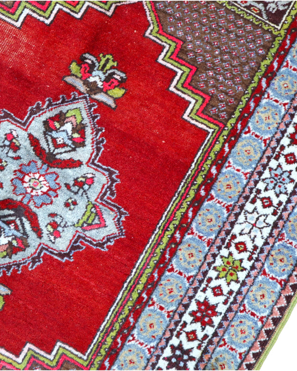 Tappeto Turco 170x108 cm annodato a mano, con campo rosso, medaglione bianco centrale e bordo riccamente decorato.