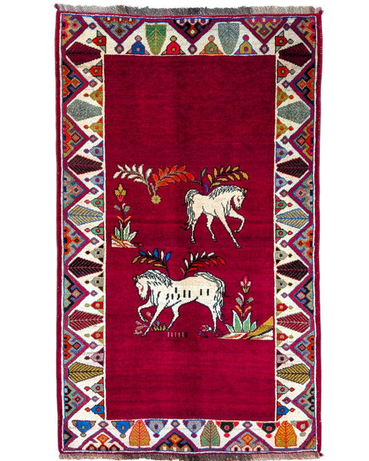 Tappeto Gashgai 185x111 cm annodato a mano, con cavalli stilizzati bianchi su fondo rosso e cornice geometrica multicolore.