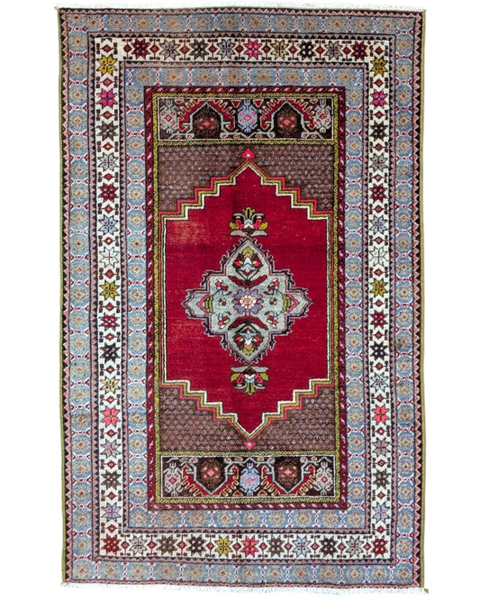 Tappeto Turco 170x108 cm annodato a mano, con campo rosso, medaglione bianco centrale e bordo riccamente decorato.