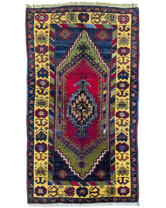 Tappeto Turco 179x103 cm, annodato a mano, con medaglione centrale geometrico rosso, motivi tribali e bordura gialla decorata.