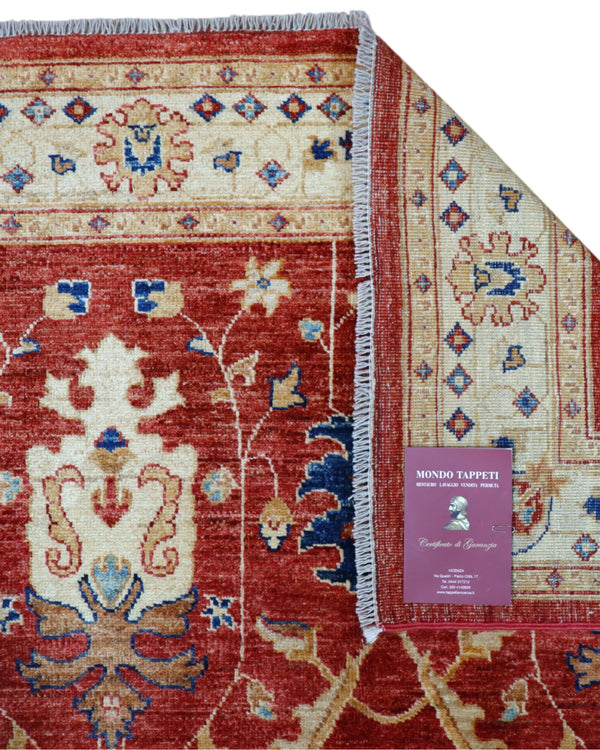 Tappeto Ziegler 170x120 cm con fondo rosso bordeaux e motivi floreali avorio e blu, tramato ed annodato a mano, provenienza Afghanistan.