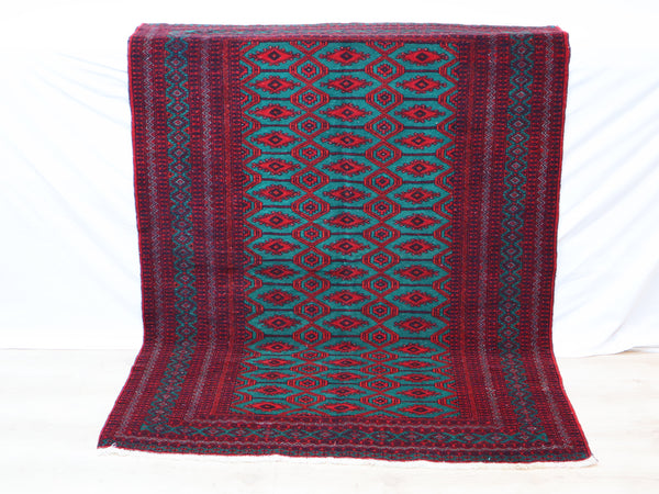 Tappeto Bukhara 172x126 cm annodato a mano, con motivi geometrici gul su fondo verde smeraldo e cornice rossa.