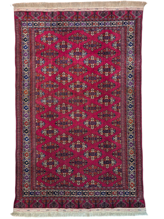 Tappeto Bukhara 280x180 cm con fondo rosso rubino e motivi geometrici ripetuti, tramato ed annodato a mano, provenienza Asia Centrale.