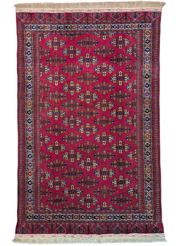 Tappeto Bukhara 280x180 cm con fondo rosso rubino e motivi geometrici ripetuti, tramato ed annodato a mano, provenienza Asia Centrale.