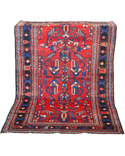 Tappeto Hamedan 200x130 cm persiano, rettangolare, annodato a mano, fondo rosso con motivi geometrici e floreali blu e avorio, bordi decorati.