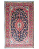 Tappeto Kashan persiano 225x142 cm, annodato a mano, fondo blu notte con motivo floreale e cornice rossa decorata, lana mista seta, certificato di autenticità incluso.