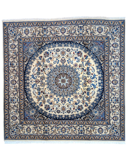 Tappeto Nain con medaglione floreale stilizzato su fondo beige e dettagli celesti, annodato a mano in Persia con lana mista seta e cotone.