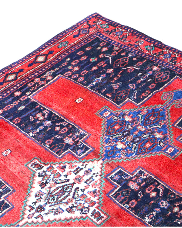 Tappeto Senneh 175x124 cm persiano, annodato a mano, fondo rosso con tre medaglioni geometrici blu e avorio, motivi floreali stilizzati.