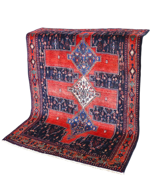 Tappeto Senneh 175x124 cm persiano, annodato a mano, fondo rosso con tre medaglioni geometrici blu e avorio, motivi floreali stilizzati.