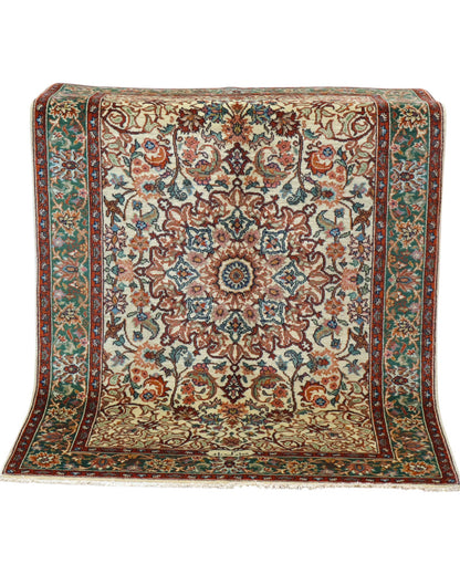 Tappeto Transilvania 180x130 cm annodato a mano, rettangolare, in lana e cotone, fondo avorio con medaglione centrale marrone e motivi floreali in verde, azzurro e rosso.