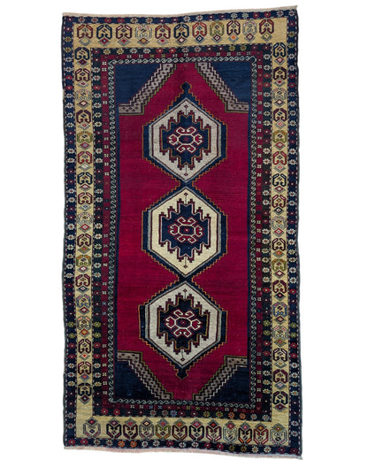 Tappeto Turko 273x149 cm annodato a mano, rettangolare, fondo rosso intenso con tre medaglioni geometrici blu e avorio, cornice decorata con motivi anatolici.