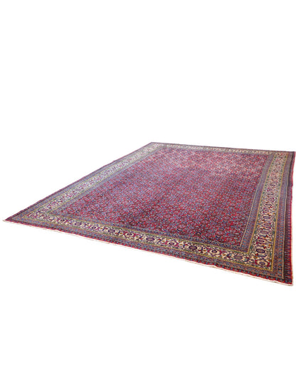 Tappeto Ushak 424x320 cm, fondo rosso con motivi ripetuti geometrici e floreali, cornice giallo-avorio, annodato a mano in lana vegetale, Turchia.