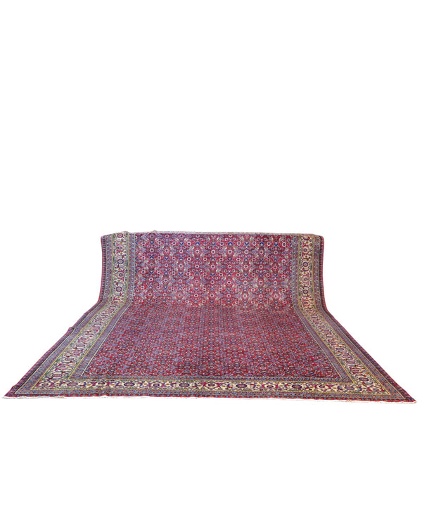 Tappeto Ushak 424x320 cm, fondo rosso con motivi ripetuti geometrici e floreali, cornice giallo-avorio, annodato a mano in lana vegetale, Turchia.