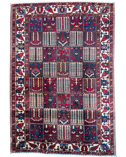Tappeto persiano Bakhtiar 306x211 cm, motivo a pannelli con decorazioni floreali e geometriche in rosso, blu e avorio, annodato a mano in lana vegetale.