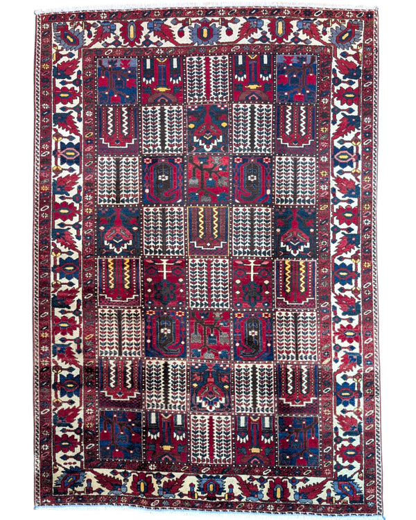 Tappeto persiano Bakhtiar 306x211 cm, motivo a pannelli con decorazioni floreali e geometriche in rosso, blu e avorio, annodato a mano in lana vegetale.