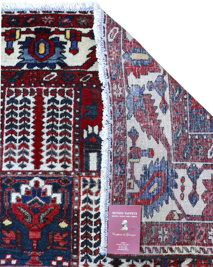 Tappeto persiano Bakhtiar 306x211 cm, motivo a pannelli con decorazioni floreali e geometriche in rosso, blu e avorio, annodato a mano in lana vegetale.