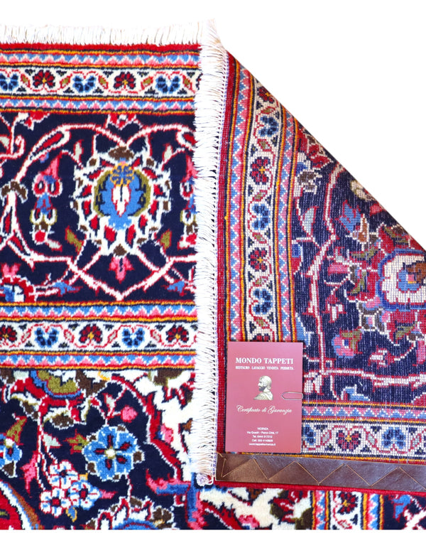 Tappeto persiano Kashan 370x250 cm, fondo rosso con medaglione centrale e cornice blu floreale, annodato a mano in lana vegetale.