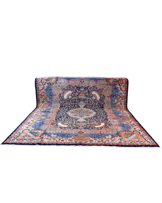 Tappeto persiano Kashmar 384x293 cm, fondo blu con medaglione centrale e motivi floreali e figurativi, annodato a mano in lana vegetale.