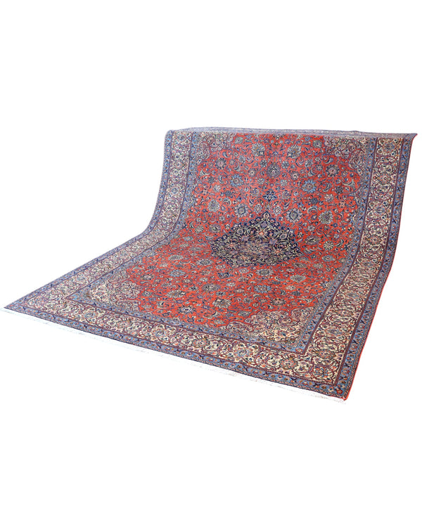 Tappeto persiano Saurk 345x240 cm, fondo rosso corallo con medaglione blu e cornice floreale chiara, annodato a mano in lana vegetale.