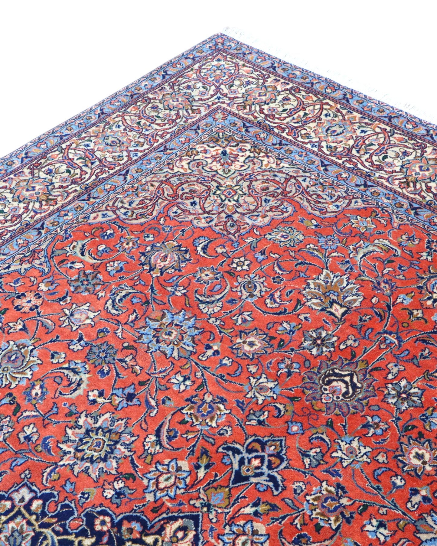 Tappeto persiano Saurk 345x240 cm, fondo rosso corallo con medaglione blu e cornice floreale chiara, annodato a mano in lana vegetale.